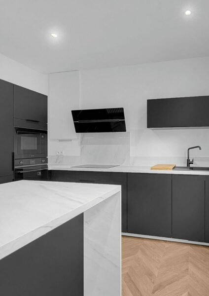 Cuisine moderne avec armoires noires et plans de travail en marbre blanc