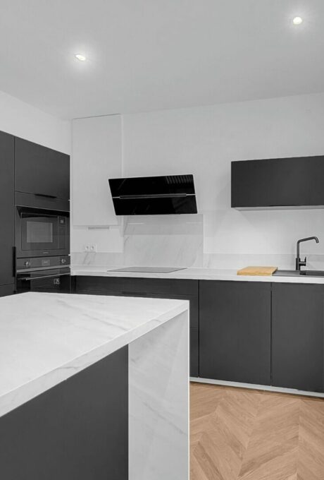 Cuisine moderne avec armoires noires et plans de travail en marbre blanc