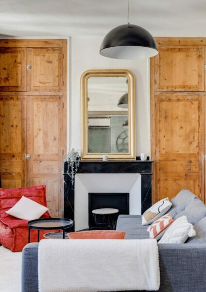 Salon avec armoires en bois, cheminée en marbre noir et miroir doré