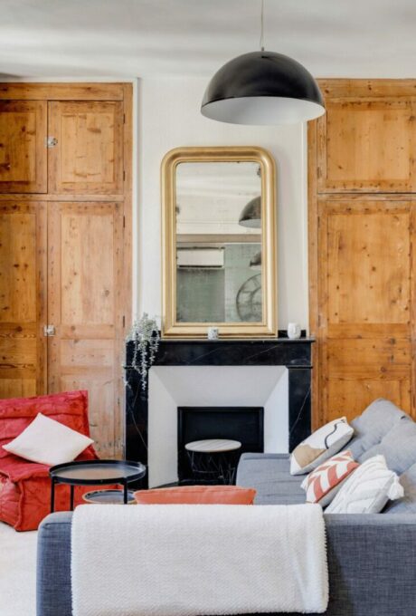 Salon avec armoires en bois, cheminée en marbre noir et miroir doré