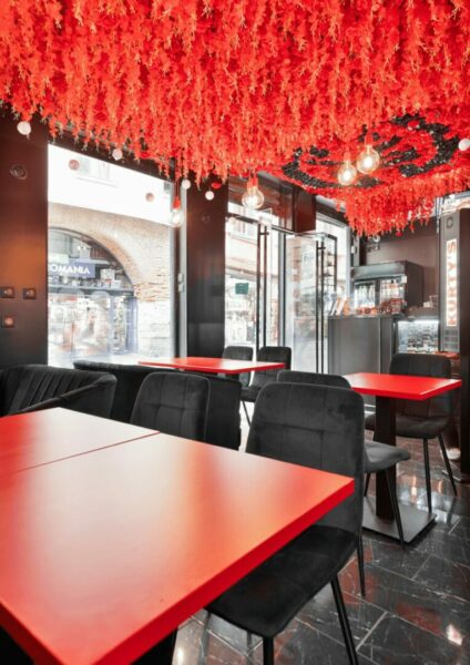 Intérieur de restaurant contemporain avec tables rouges et décorations au plafond