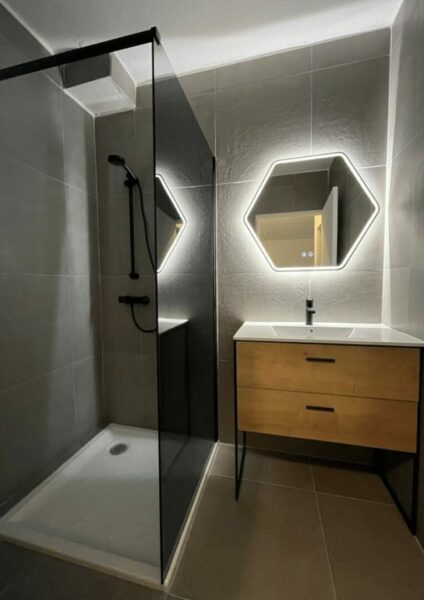 Salle de bain moderne avec miroirs hexagonaux, douche noire et meuble-vasque en bois
