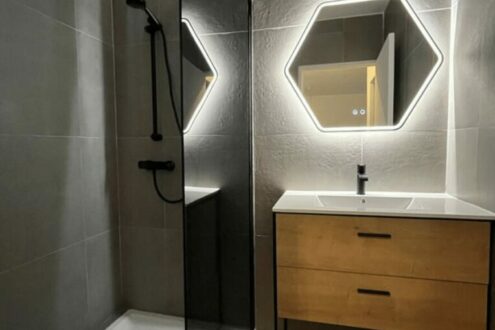 Salle de bain moderne avec miroirs hexagonaux, douche noire et meuble-vasque en bois