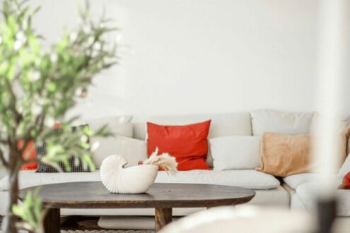 Salon élégant avec canapé d'angle beige, coussins rouges et décoration artistique