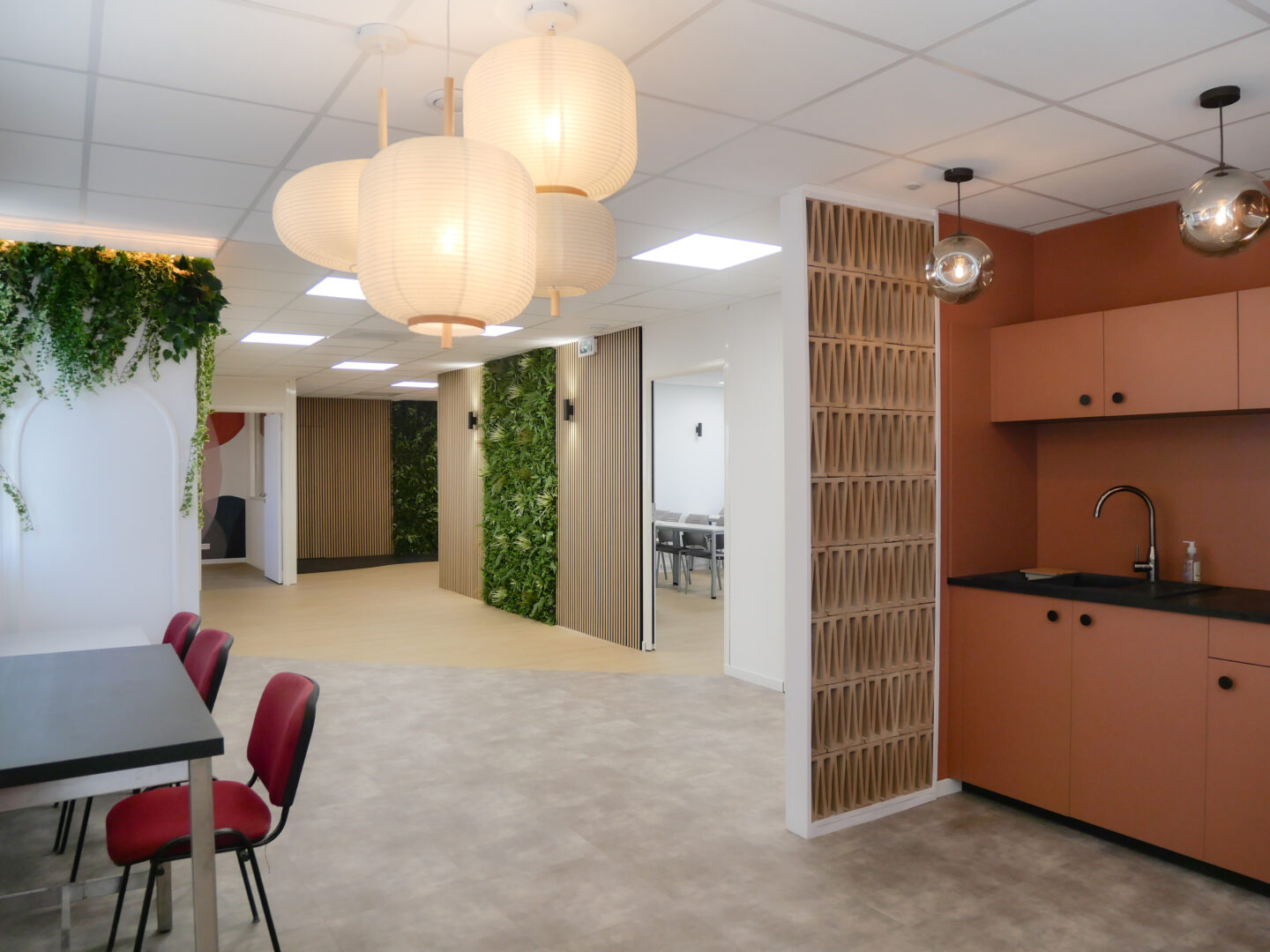 Espace commun d'un local professionnel à Toulouse, comprenant une cuisine moderne et un mur végétal décoratif.