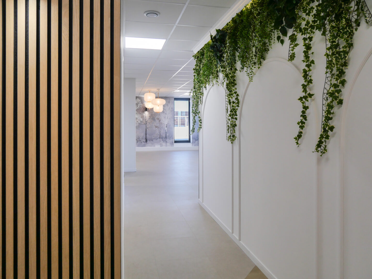 Intérieur moderne d'un espace professionnel à Toulouse avec un mur végétal et des luminaires suspendus, conçu par une agence d'architecture.