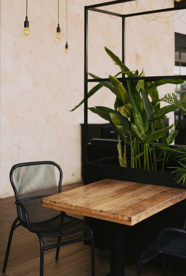 table en bois avec chaises noire et plantes